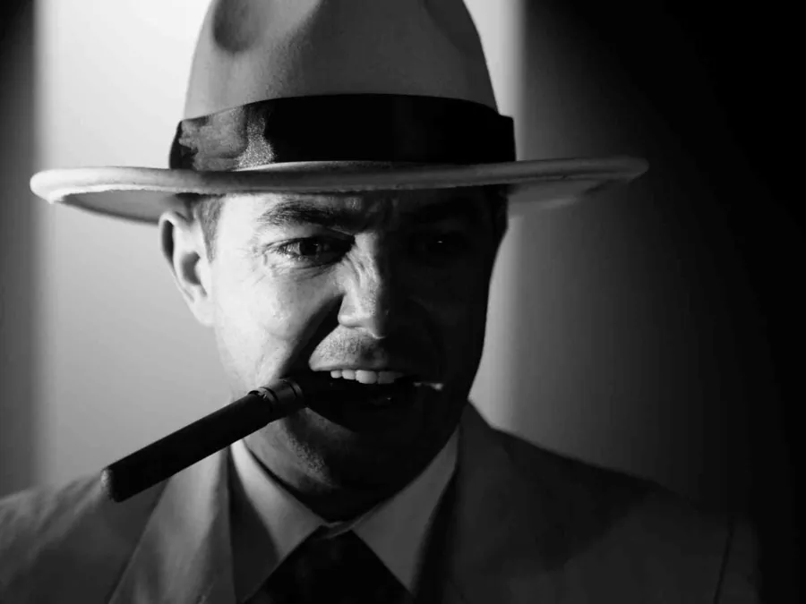 A man in a white fedora with a cigar