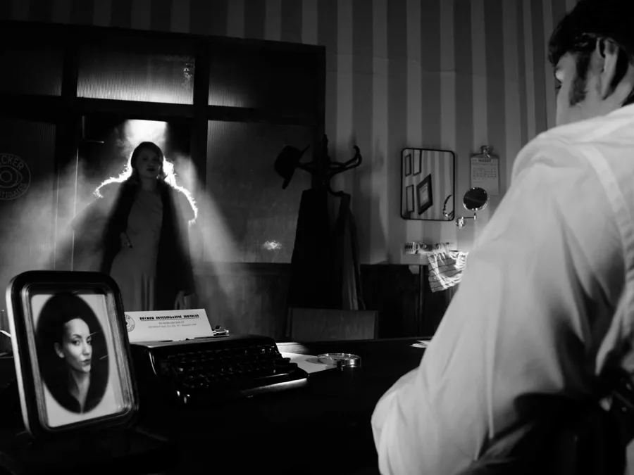 A man at a typewriter as a figure appears behind him