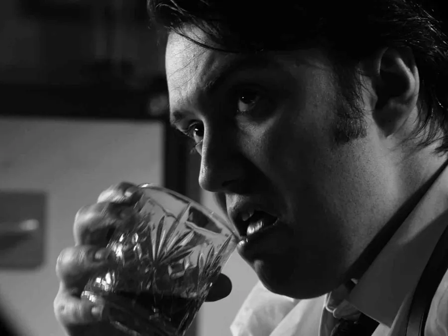 A man drinking from a crystal glass